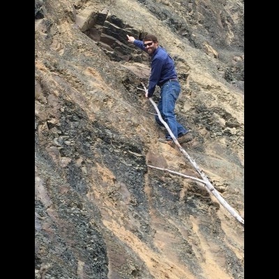 Pat points out an Eocene aged palm frond fossil along the highway near Palmer, Alaska.