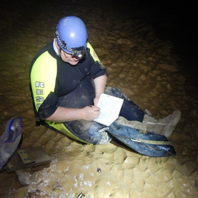 JP sitting on the drained floor of a underground river at Mammoth Cave National Park in October 2020, documenting hundreds of shark teeth and spines that are littering the wall, ceiling, and floor of this river passage. Note his crazy field clothes of a wet suit, caving helmet, and hiking boots. (Photo by Rick Toomey/NPS)