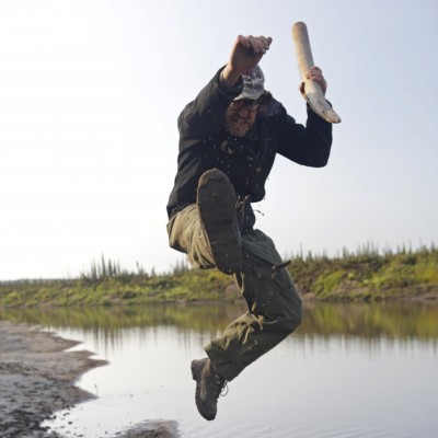 Although he deals with thousands of specimens, Grant still jumps with joy when he finds them.&nbsp; Here he is celebrating finding a tusk on the Old Crow River in 2018.