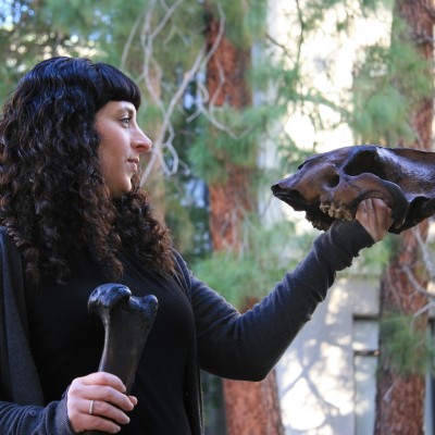 Julie at the Campanile at Berkeley holding up Smilodon&rsquo;s skull and humerus